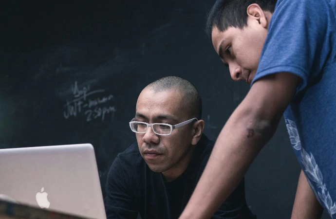 two men watching on silver MacBook